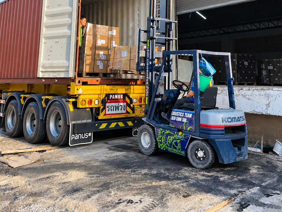 Forklift beside an open shipping container at a warehouse loading bay